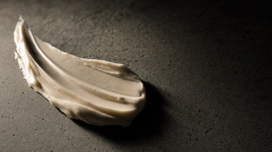 Ivory tallow-based cream swiped across dark grey concrete