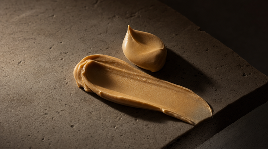 Golden grass-fed tallow cream swatch on a warm stone slab